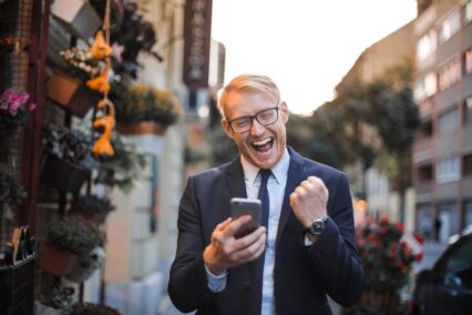 happy man walking down the road looking at phone