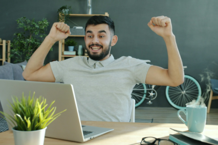 happy man with arms in the air in home office