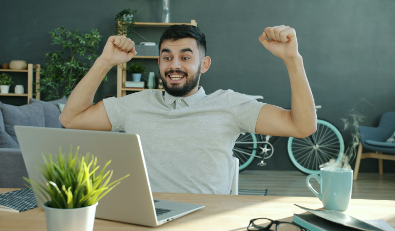 happy man with arms in the air in home office