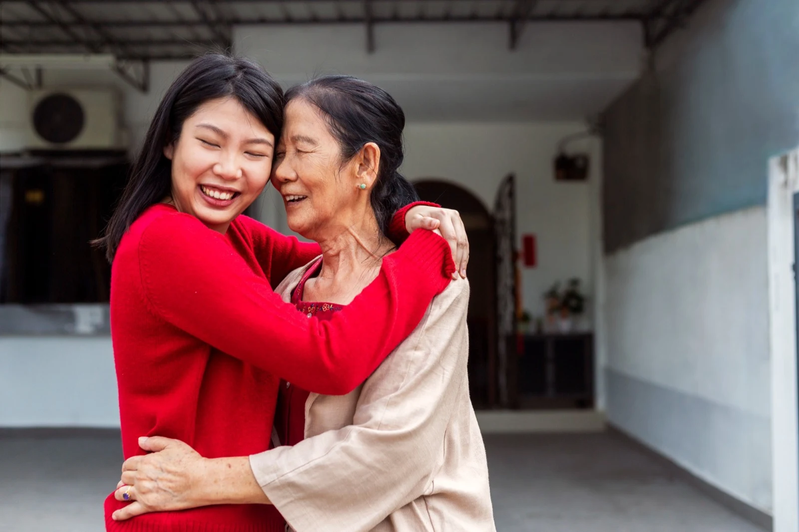 Daughter hugging her mother outside their home