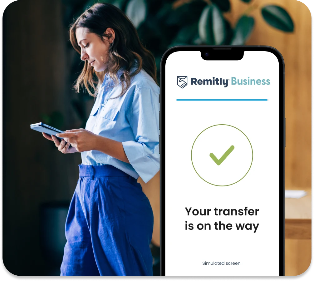 Business owner checking a tablet beside a phone showing “Your transfer is on the way”